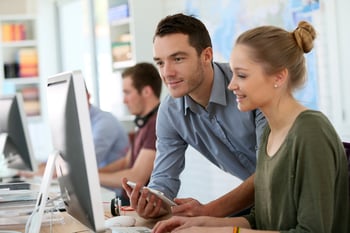 Lehrlinge arbeiten am Schreibtisch mit Computer in einer entspannten Atmosphäre