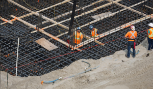 Mehrere Bauarbeiter arbeiten auf einer Baustelle und errichten ein Fundament.