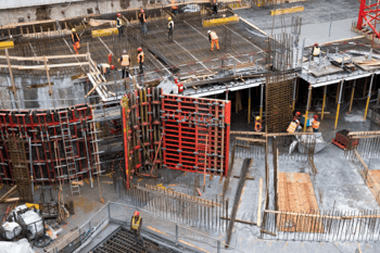 Bauarbeiter arbeiten auf einer Baustelle, umgeben von Maschinen und Materialien.