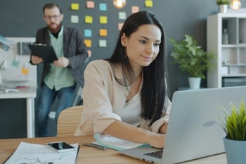 Eine Frau arbeitet an einem Laptop in einem modernen Büro.
