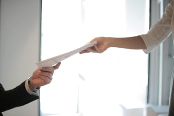 Ein Mann reicht einer Frau ein Dokument.