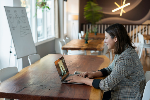 Eine Frau sitzt an einem Tisch und arbeitet an ihrem Laptop. 