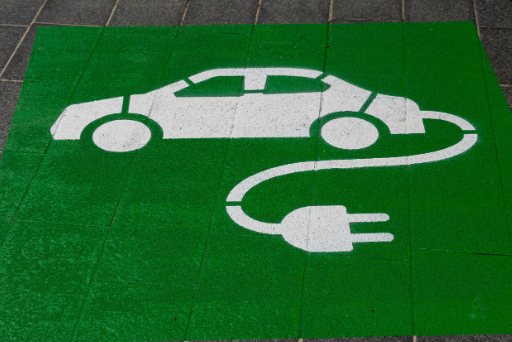 Eine grün aufgemalte Bodenmarkierung zeigt ein Elektroauto, das an ein Ladegerät angeschlossen ist.