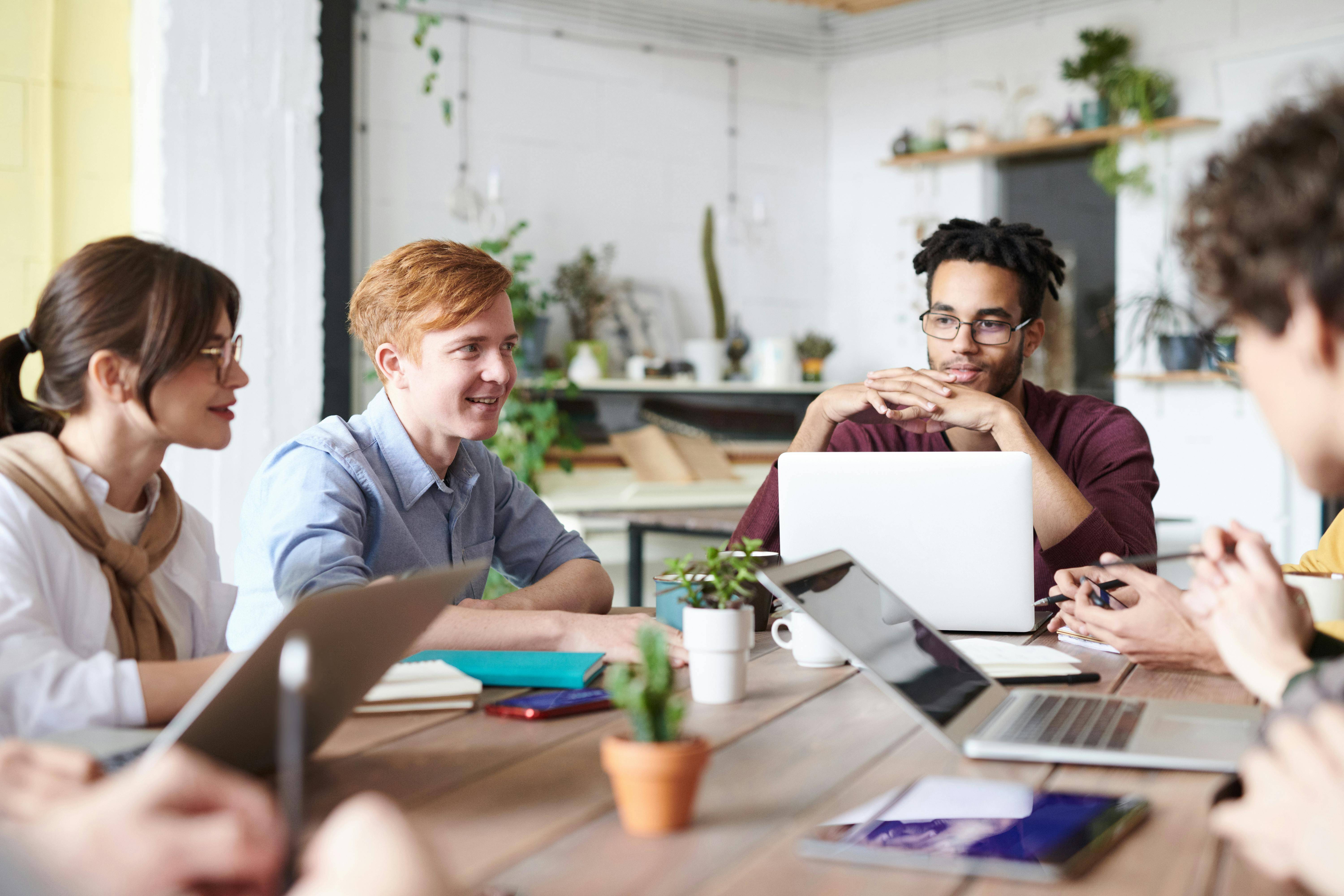  Mehrere Personen sitzen an einem Tisch mit Laptops und arbeiten zusammen. 