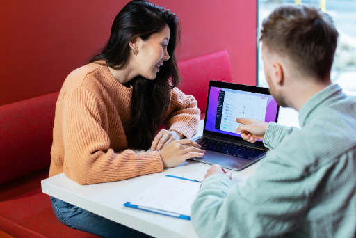 Ein Mann und eine Frau sitzen an einem Tisch und arbeiten gemeinsam an einem Laptop.
