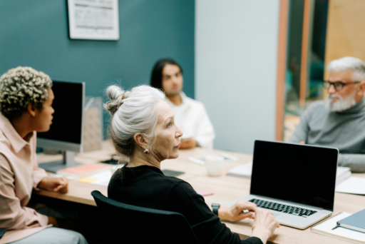 Mehrere Personen arbeiten an einem Tisch mit Laptops. 